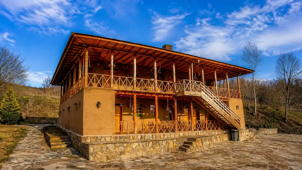 اقامتگاه بومگردی در رودبار با معماری سنتی، ایوان چوبی، چشمانداز کوهستان و فضای روستایی در میان طبیعت گیلان.