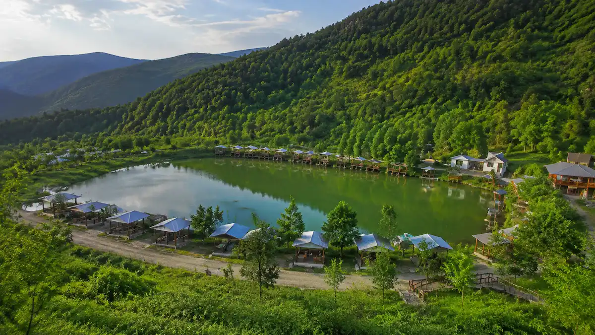 چشمانداز طبیعی رستم آباد در استان گیلان با جنگلهای انبوه، رودخانه و خانههای روستایی سنتی در دامنه کوههای البرز