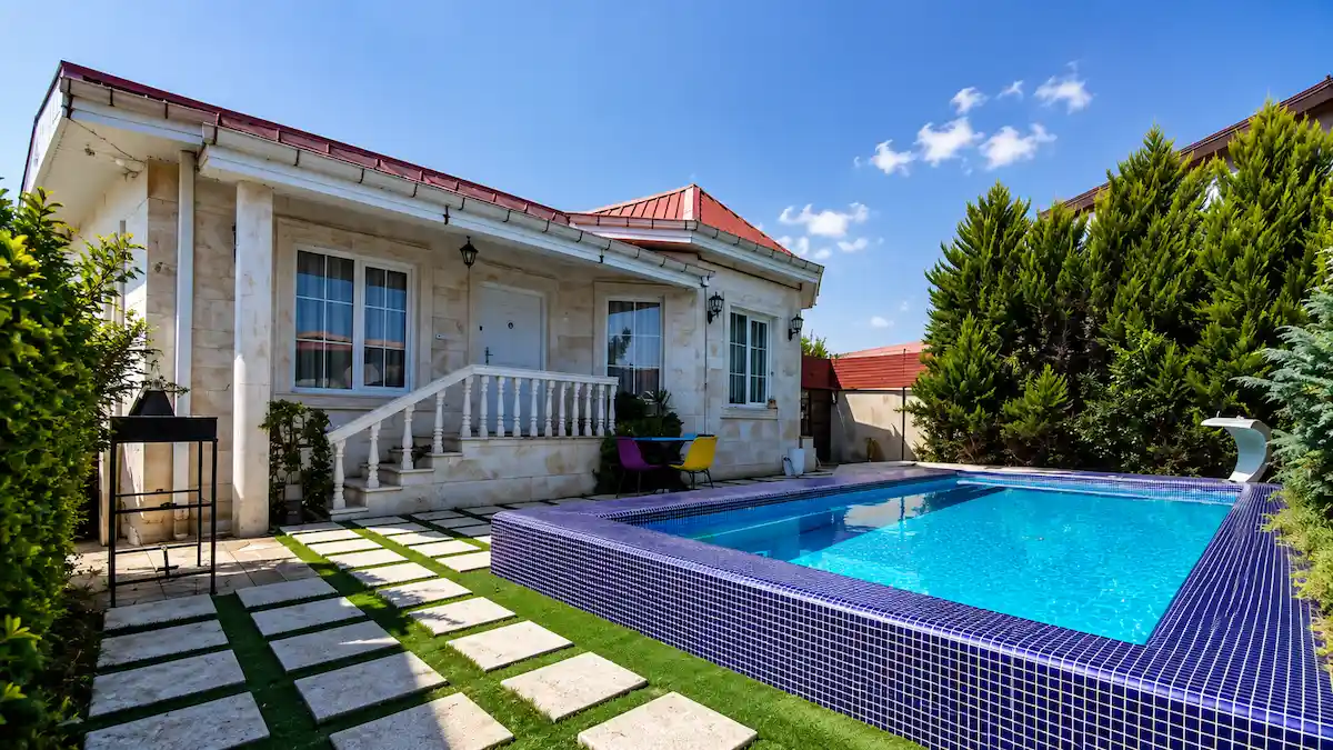 ویلای مدرن استخردار در گیلان با استخر روباز، حیاط سرسبز و منظرهای از طبیعت شمال ایران.